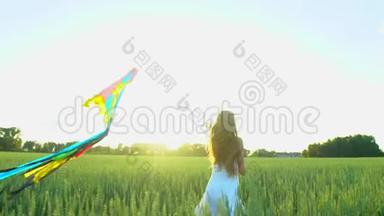 美丽的女孩，风筝随风飞舞，日落时在麦田上奔跑。 自由健康幸福理念。 快乐